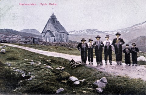Historisk bilde på folk som står fremfor Bykle kyrkje.